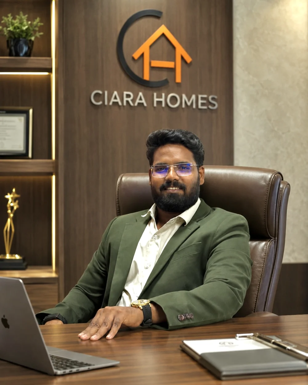 Mustaq Mahammad, founder and CEO of Ciara Homes, at his office desk below the Ciara Homes logo